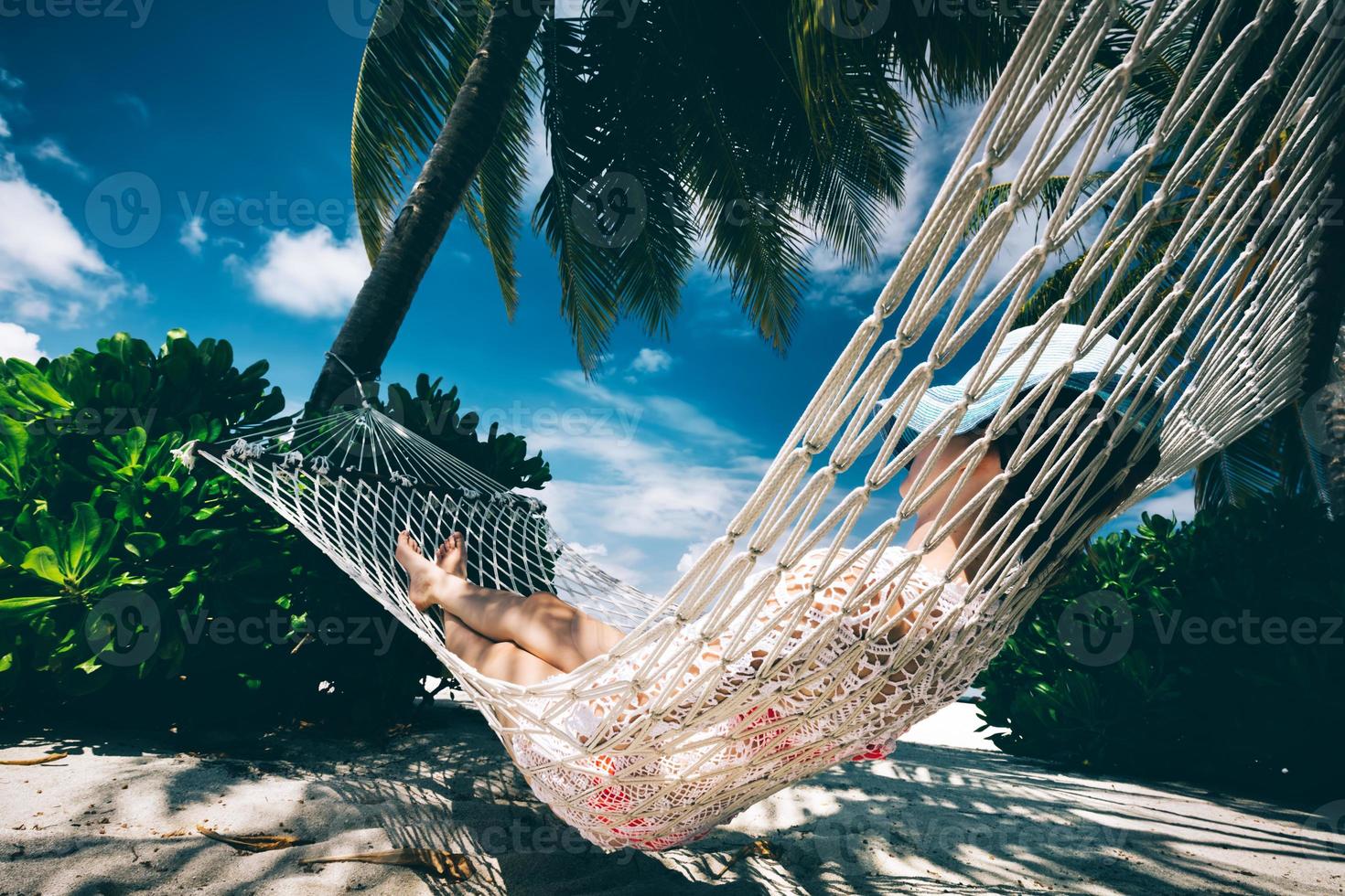 kvinna avkopplande i skuggan av palmer på en hängmatta. foto