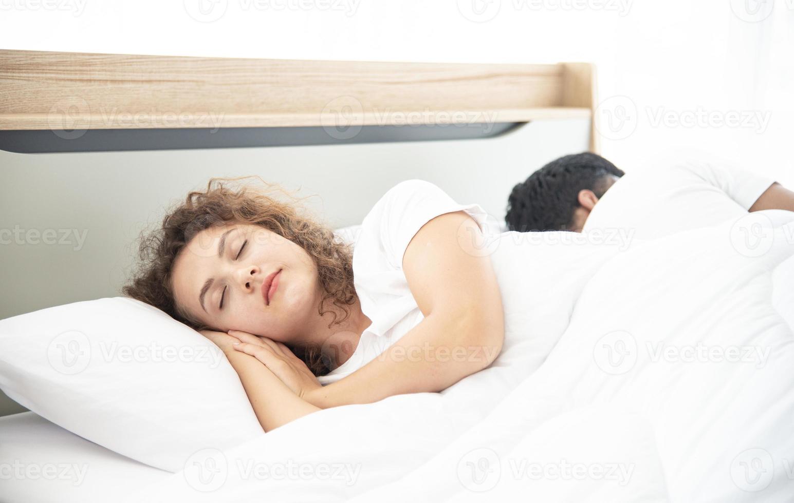 älskare koncept. unga attraktiva par liggande under vit filt i sängen foto
