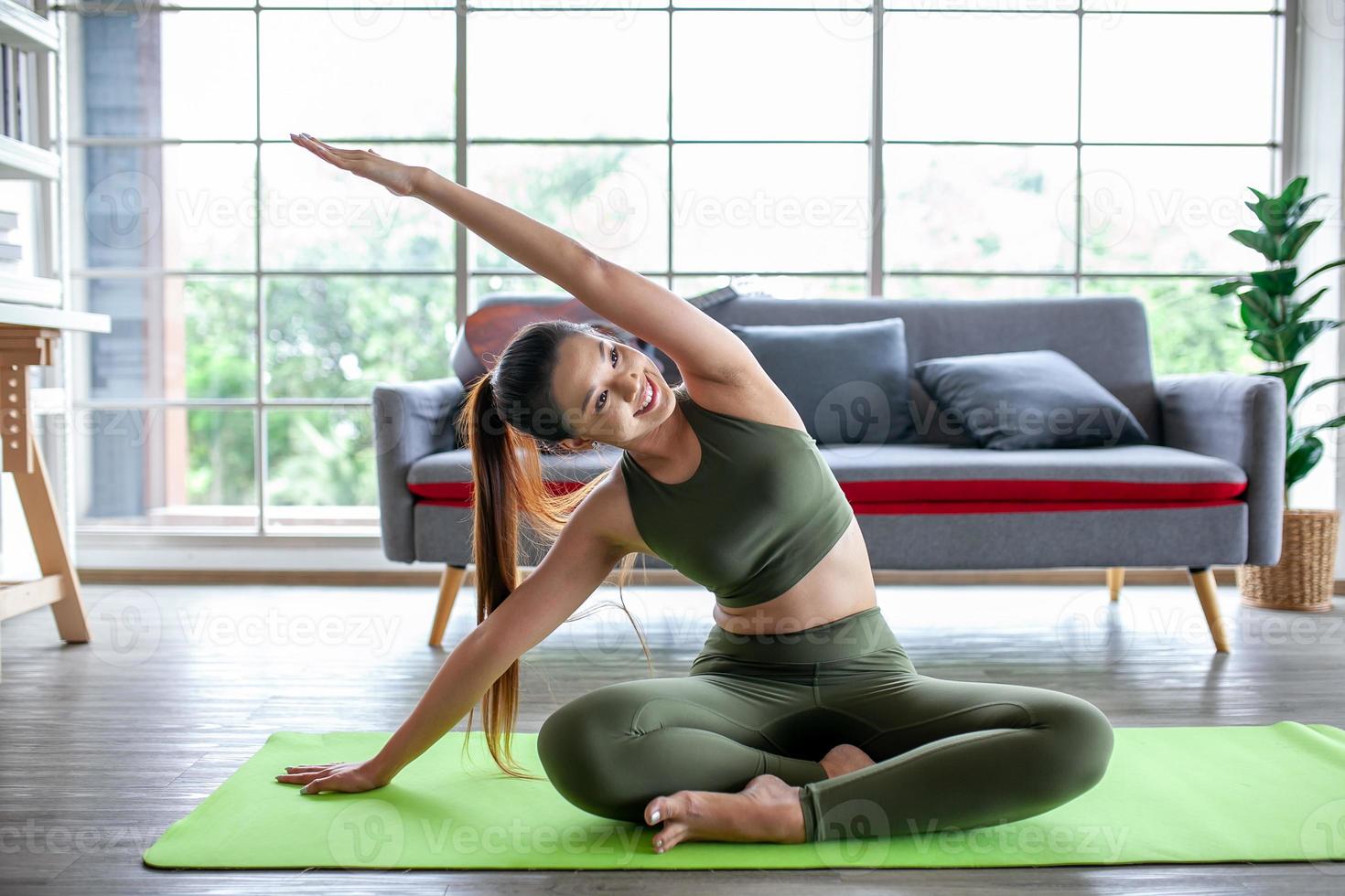 ung asiatisk kvinna tränar och gör yoga hemma, hälsosamt koncept. foto