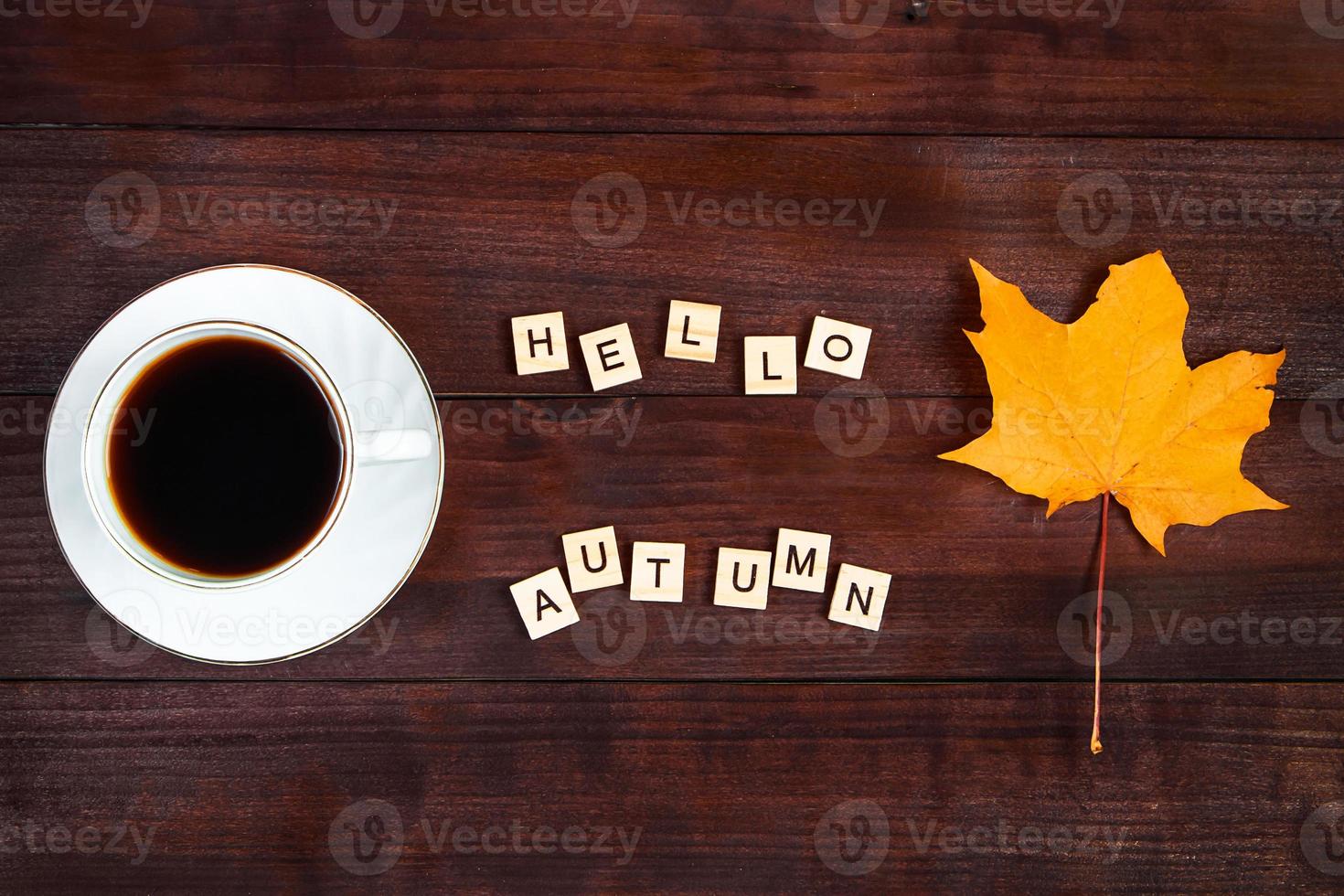 hej höst koncept. kopp kaffe och fallna löv på brun trä bakgrund. varm dryck för kallt väder. foto