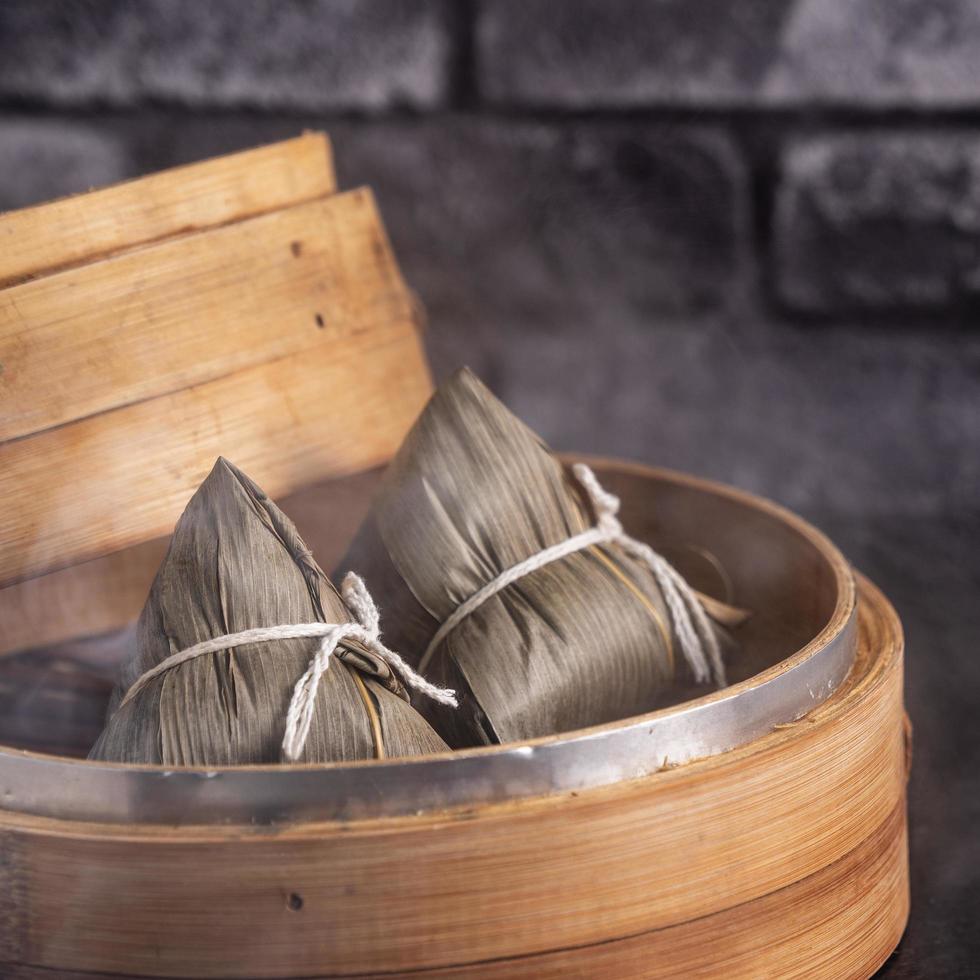 ris dumpling, zongzi - kinesisk ris dumpling zongzi på svart tegel bakgrund skiffer bord, begreppet drakbåt festival traditionell mat, närbild. foto