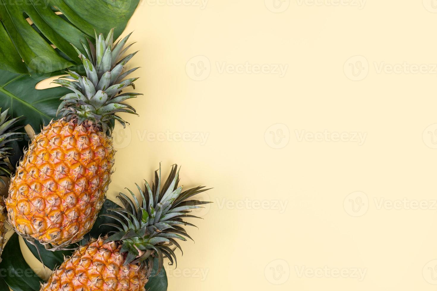 vacker ananas på tropiska palm monstera blad isolerade på ljus pastellgul bakgrund, ovanifrån, platt låg, overhead ovanför sommarfrukt. foto