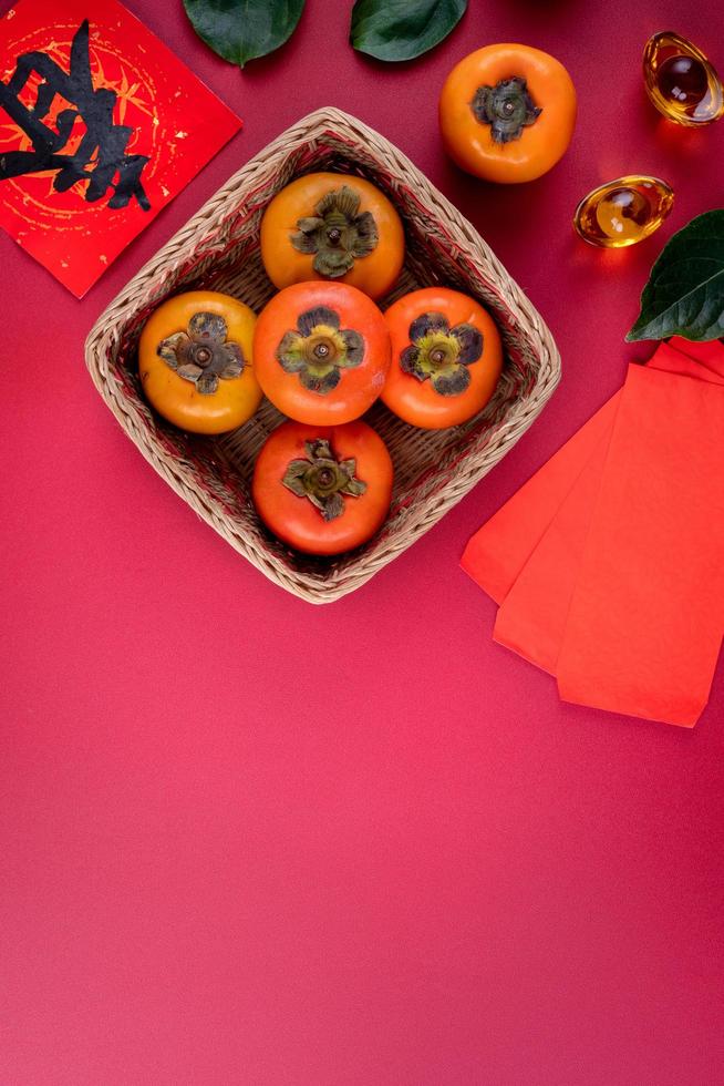ovanifrån av färska söta persimmons med löv på röd bordsbakgrund för kinesiska nyåret foto
