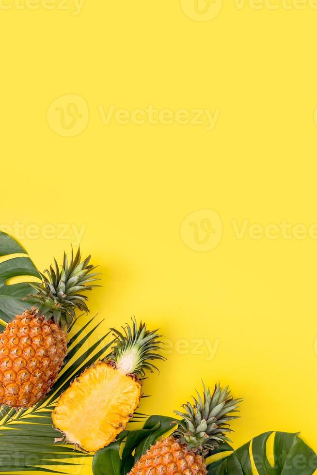 vacker ananas på tropiska palm monstera blad isolerade på ljus pastellgul bakgrund, ovanifrån, platt låg, overhead ovanför sommarfrukt. foto