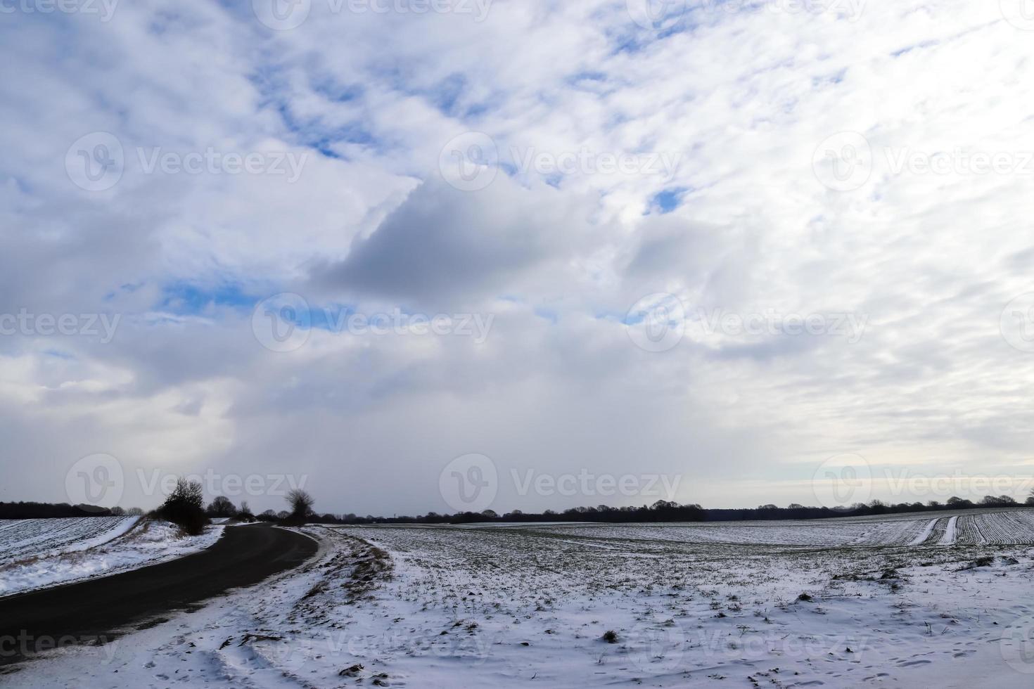 vackra moln på himlen tittar över ett snötäckt jordbruksfält. foto