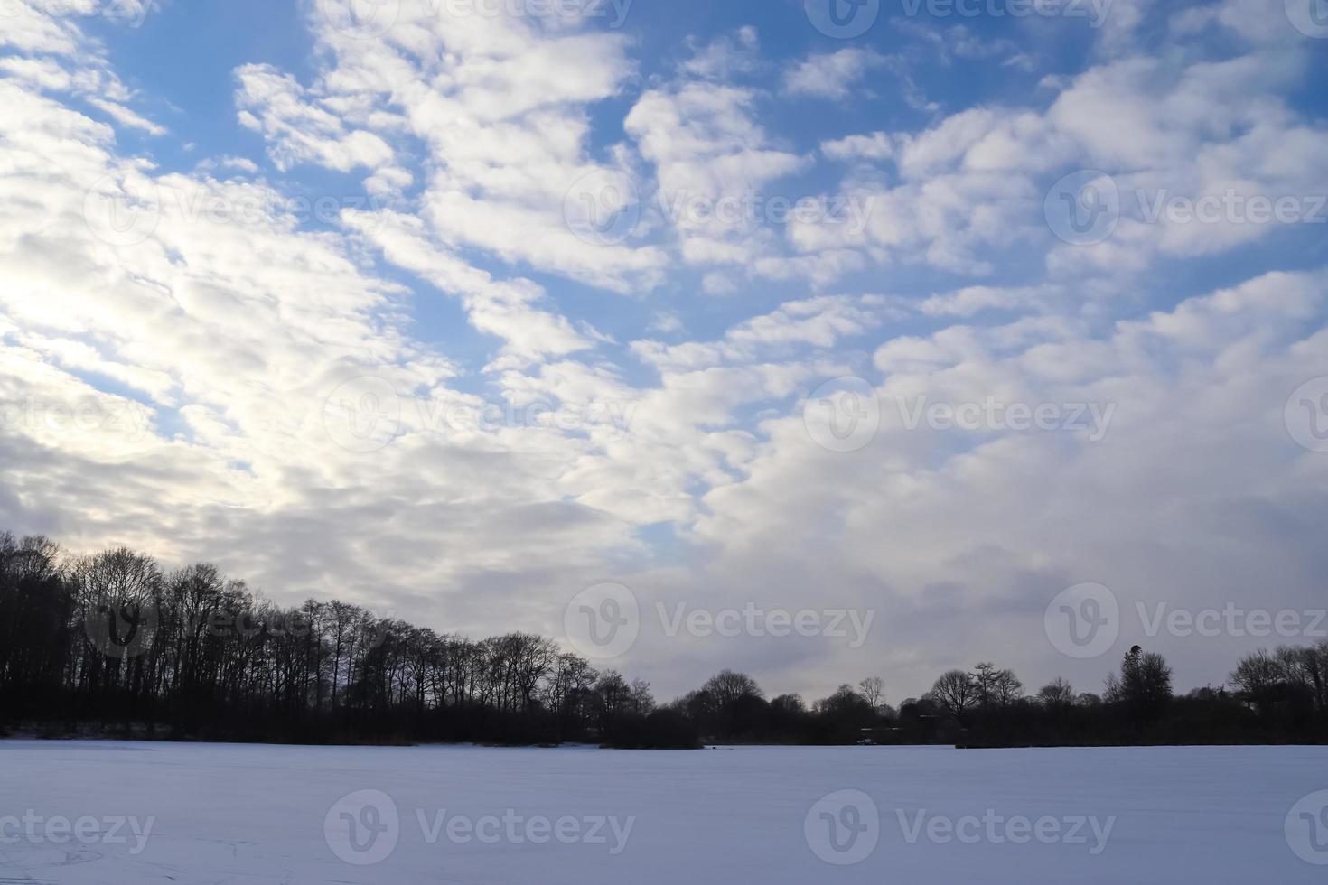 vackra moln på himlen tittar över ett snötäckt jordbruksfält. foto