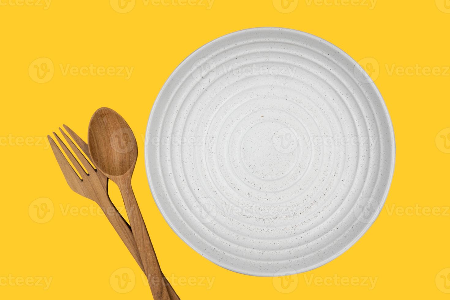 en vit rund tom tallrik med gaffel och sked på mörk bakgrund för mat- och ingredienskonceptuppsättning. isolera på gul bakgrund. foto