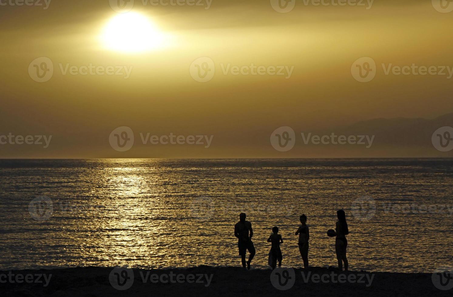 siluett av en familj under solnedgången vid kusten i Matala, Kreta foto