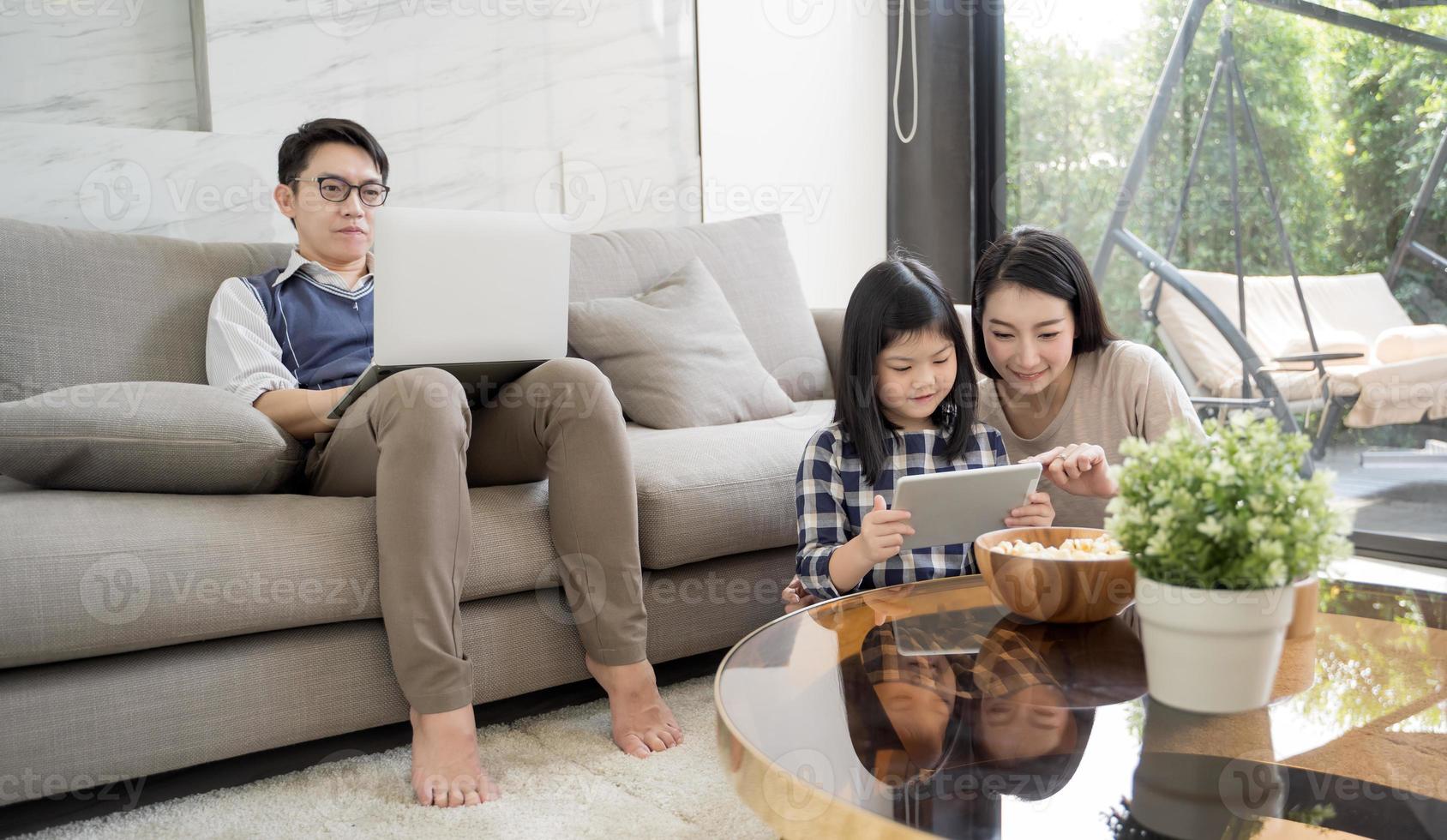 glad asiatisk familj spenderar tid tillsammans på soffan i vardagsrummet. familj och hem foto