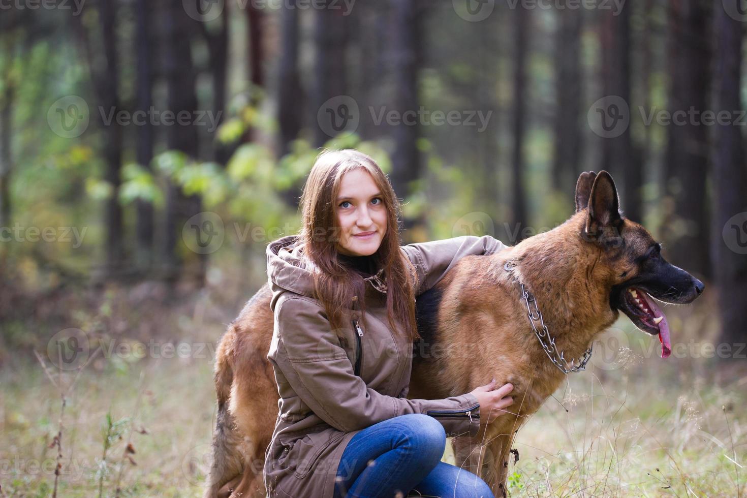 ung attraktiv kvinna poserar med schäferhund och ler utomhus i höstparken, närbild foto