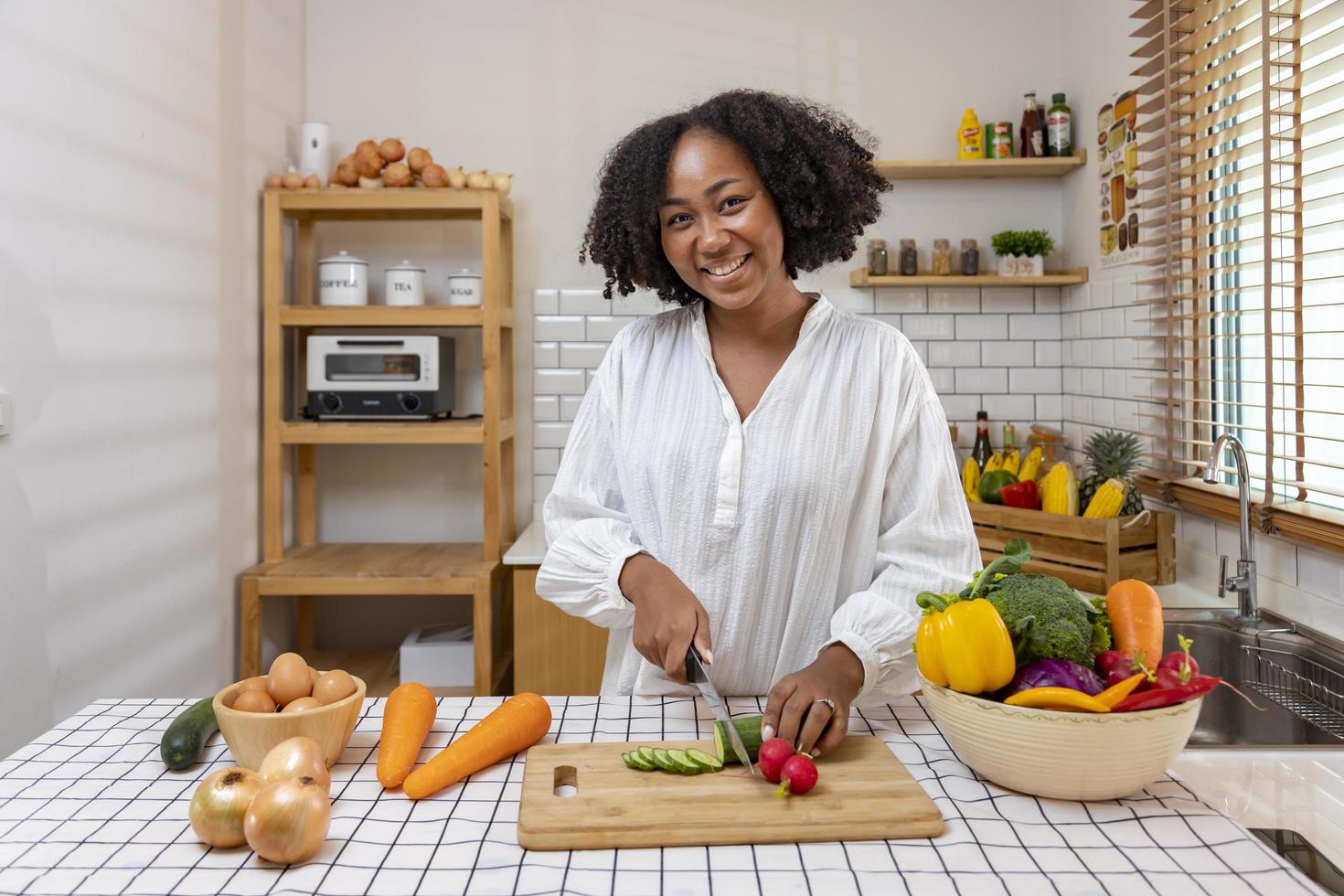 afrikansk amerikansk hemmafru hackar ekologisk gurka för att förbereda enkel och lätt salladsmåltid i sydländsk stil för vegansk och vegetarisk matkoncept foto