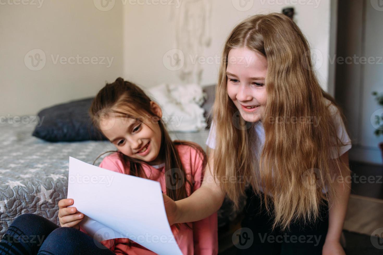 två tjejkompisar leker hemma, ritar med pennor och tuschpennor och har kul foto