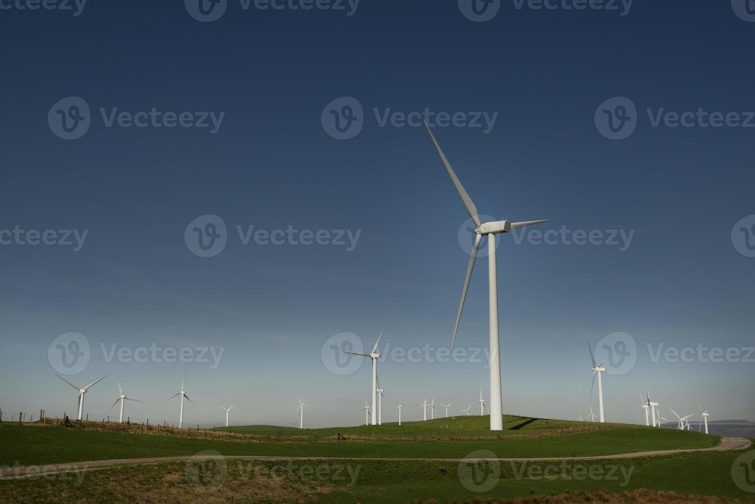 vindkraftverk med andra turbiner på toppen av en kulle foto