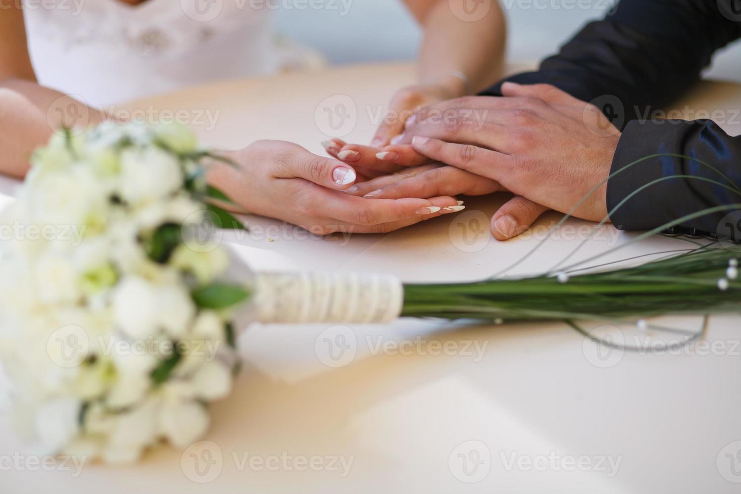 brudgummen omfamnar bruden med bröllopsbukett. ringar på händerna på nygifta par. bruden lade sina händer på brudgummens axlar. foto