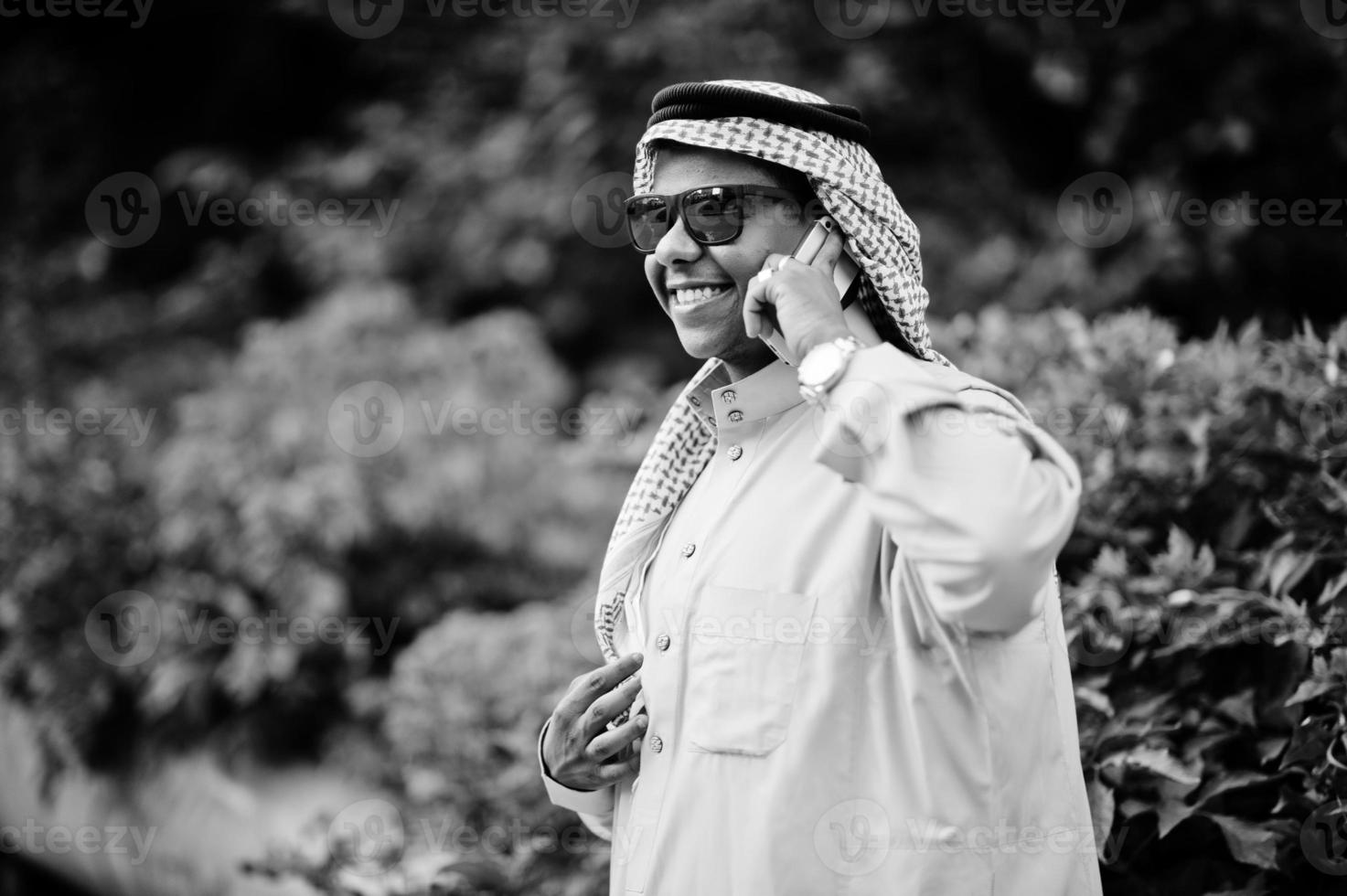 Mellanöstern arabisk affärsman poserade på gatan med solglasögon, talar i mobiltelefon. foto