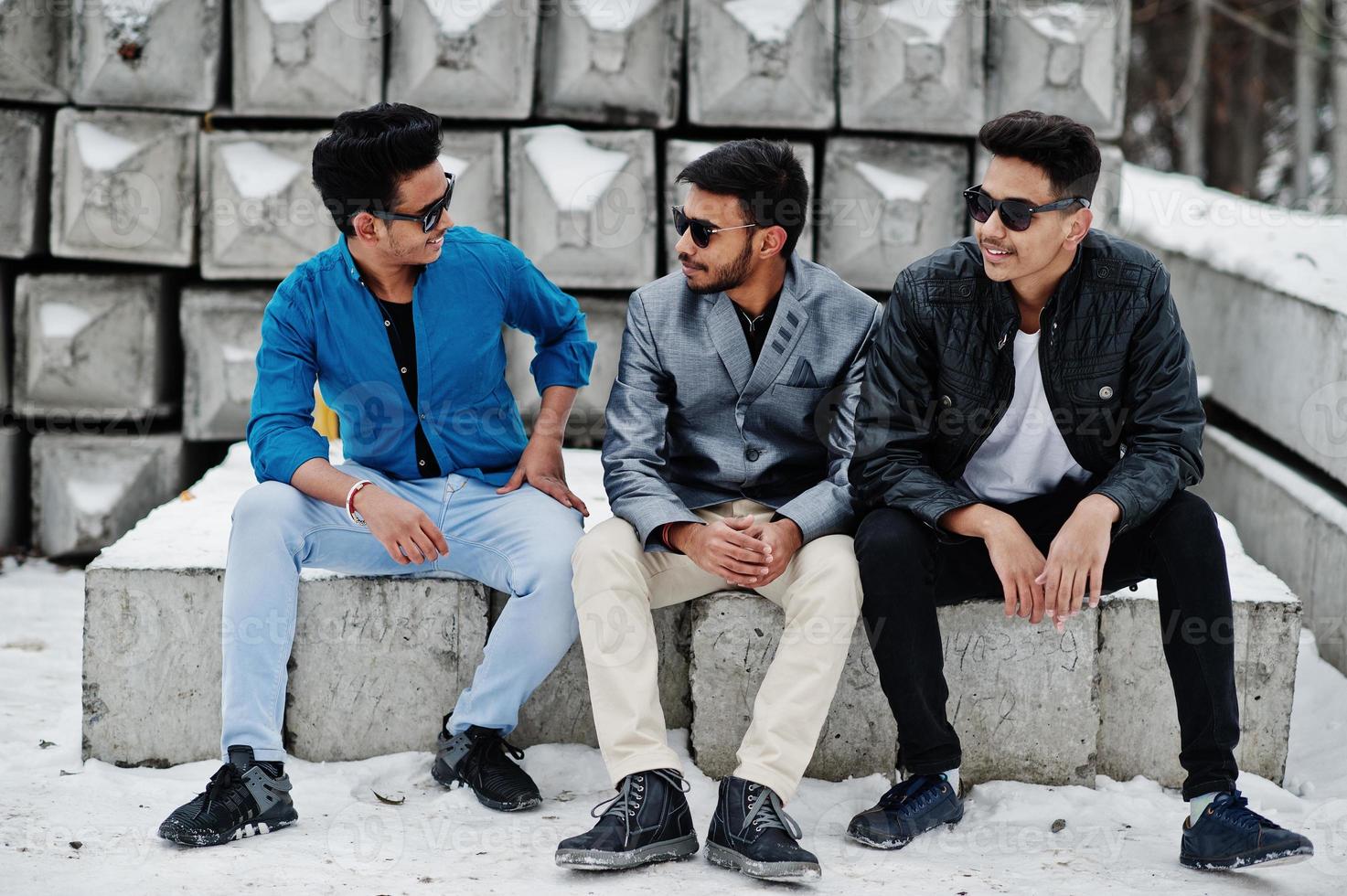 grupp av tre casual unga indiska män i solglasögon poserade mot stenblock. foto