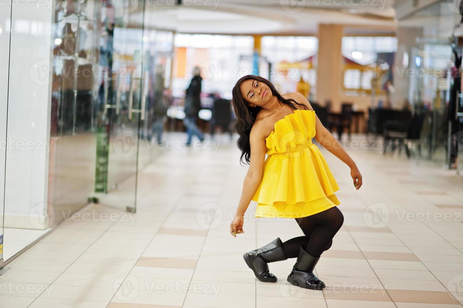 snygg afrikansk amerikansk kvinna på gul klänning poserade på köpcentret. foto