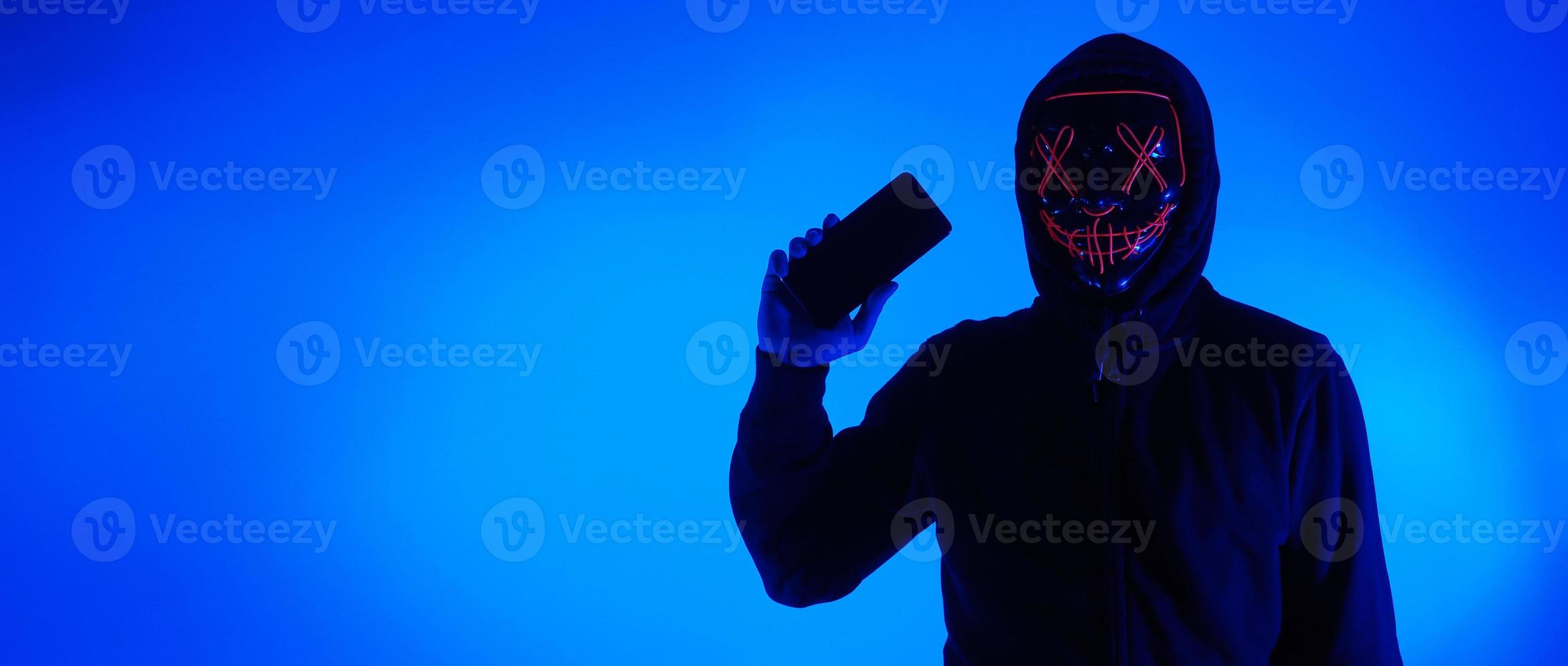 anonym hacker och ansiktsmask med smartphone i handen. foto