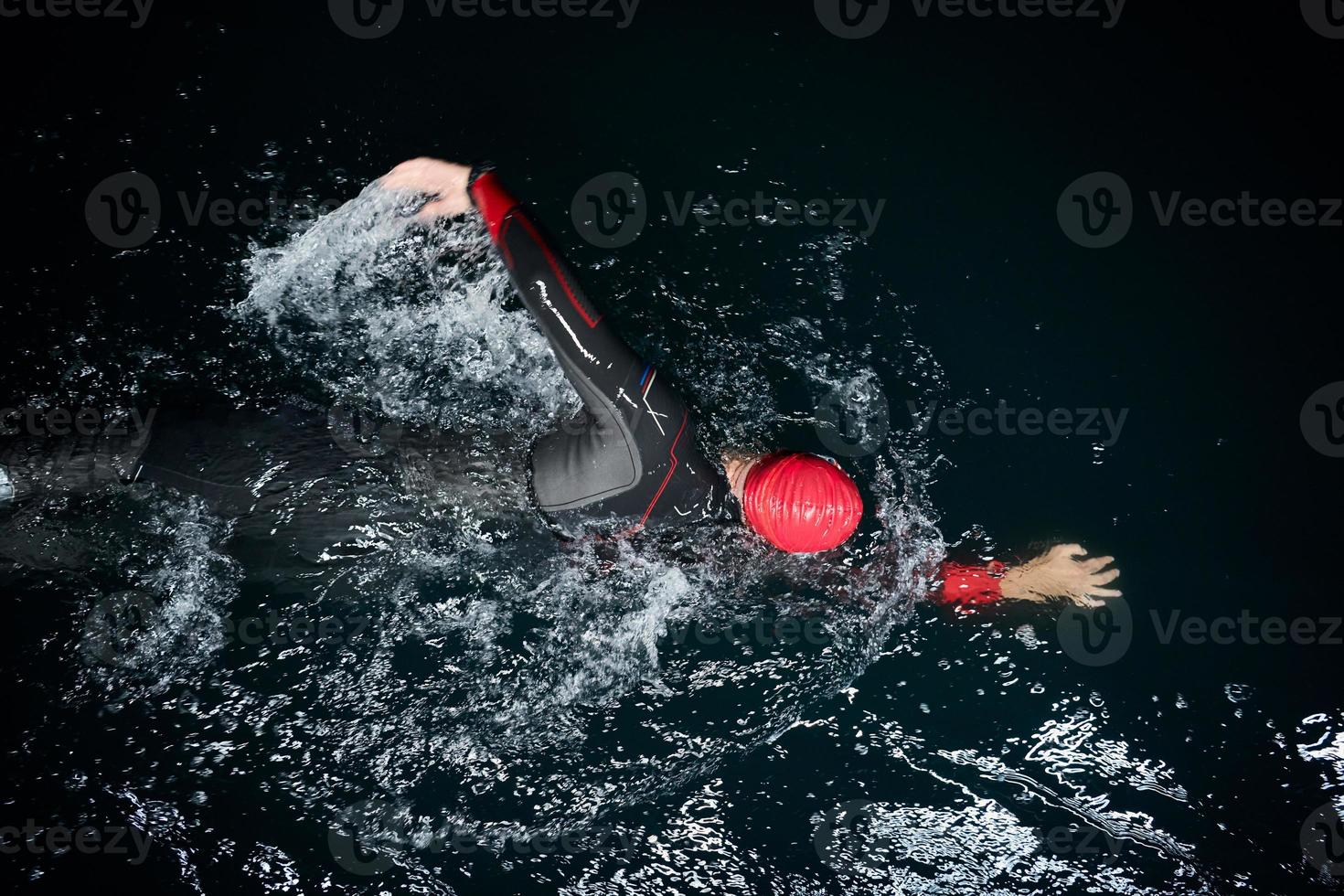 triathlon idrottare simmar i mörk natt iklädd våtdräkt foto