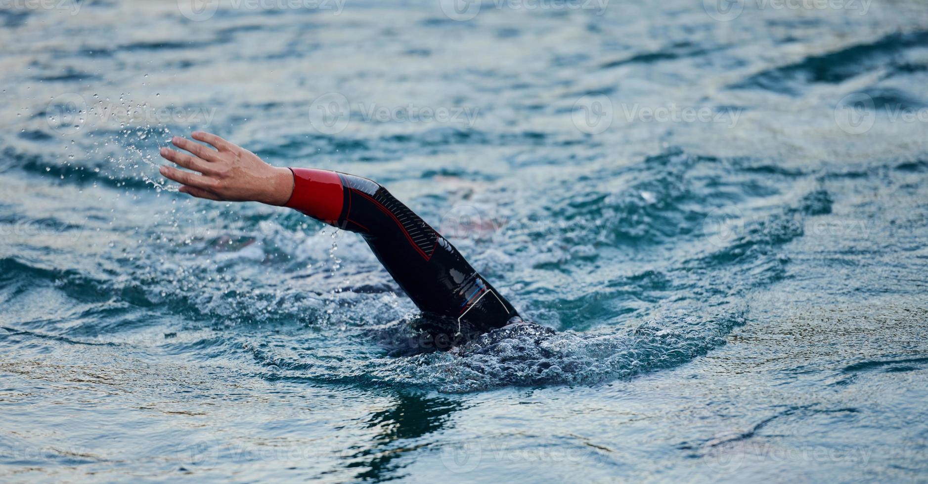 triathlon idrottare simmar på sjön i soluppgången bär våtdräkt foto