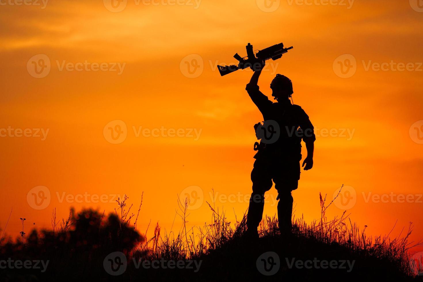 silhuett av militär soldat eller officer med vapen vid solnedgången foto