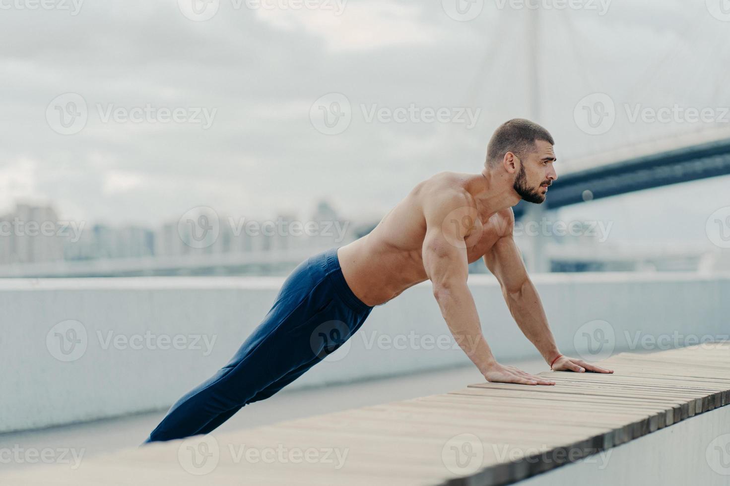 idrottsman kille står i planka pose gör push up träning utomhus andas frisk luft har en stark kropp och naken bål motivation för att hålla sig vältränad och frisk leder till en aktiv livsstil. sport träning koncept foto