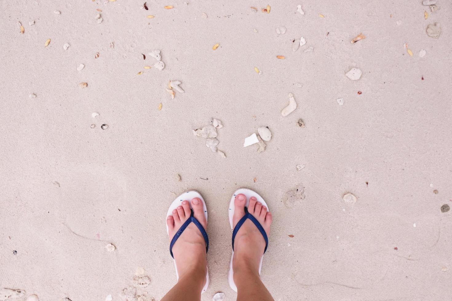 selfie av fötter i mode sandaler på sandstrand bakgrund, ovanifrån med kopia utrymme foto