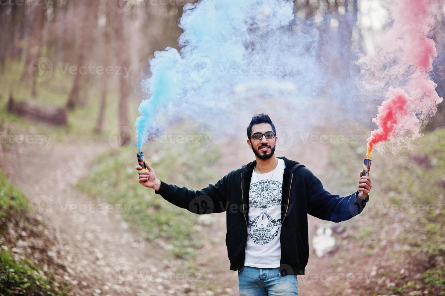 street style arab man i glasögon håller hand flare med röd och blå rök granat bomb. foto