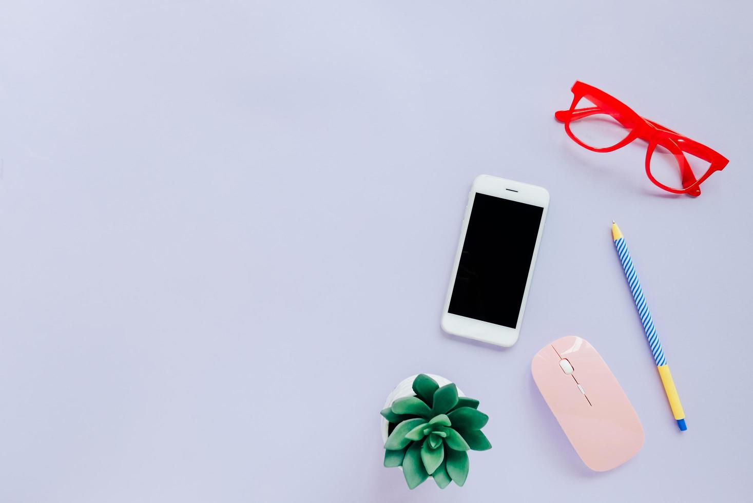 kreativt platt lay-stil arbetsyta skrivbord med smartphone, brevpapper, mus och glasögon på färgglad bakgrund med kopia utrymme foto