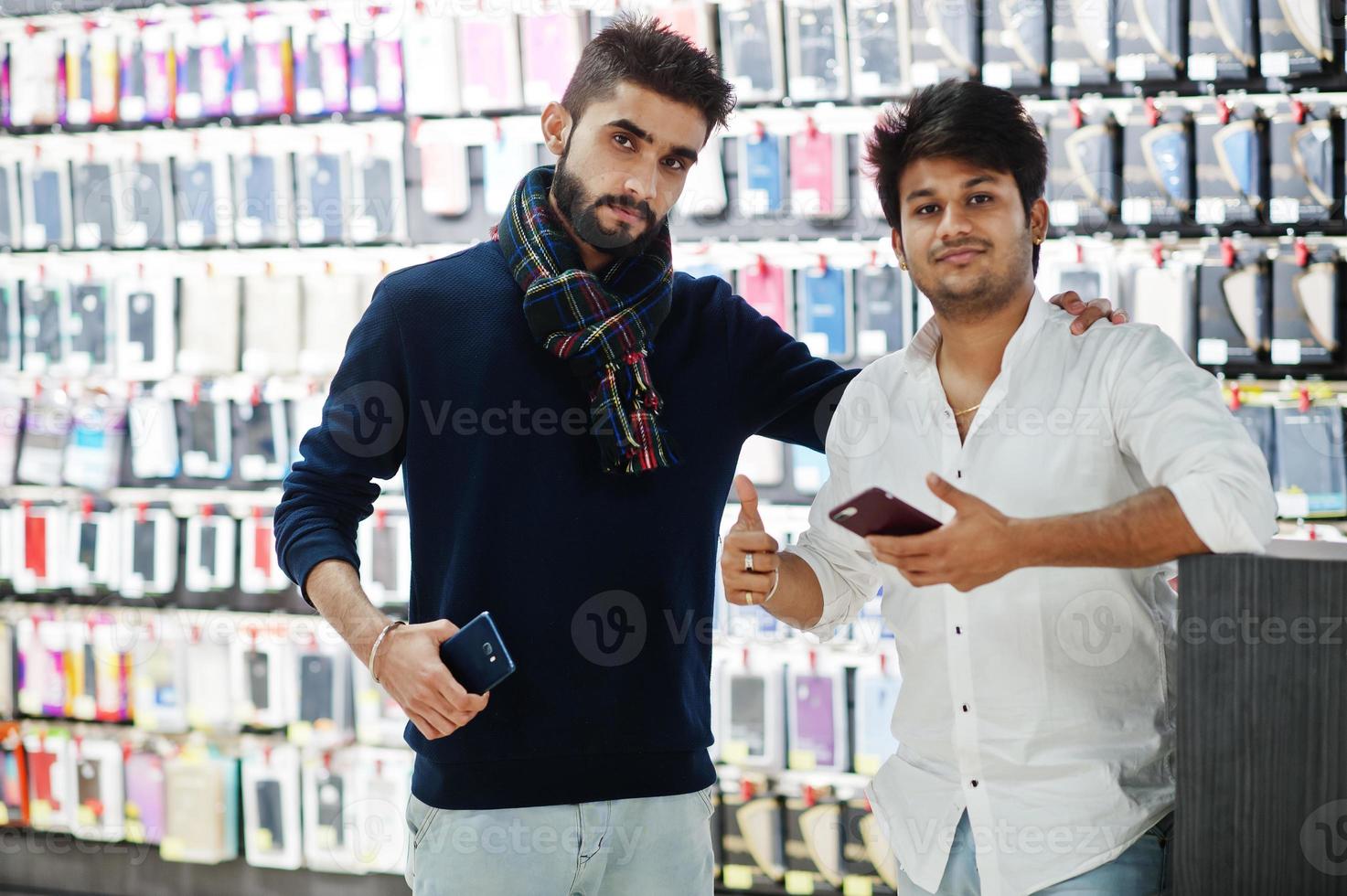 två indianer bemannar kundköpare i mobiltelefonbutik med nya smartphones. sydasiatiska folk och teknik koncept. mobiltelefon butik. foto