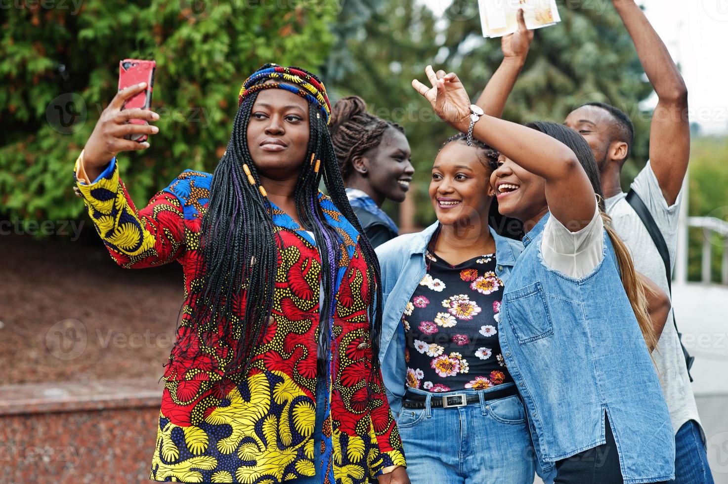 grupp på fem afrikanska högskolestudenter som spenderar tid tillsammans på campus på universitetsgården. svarta afro-vänner gör selfie på telefonen. utbildningstema. foto