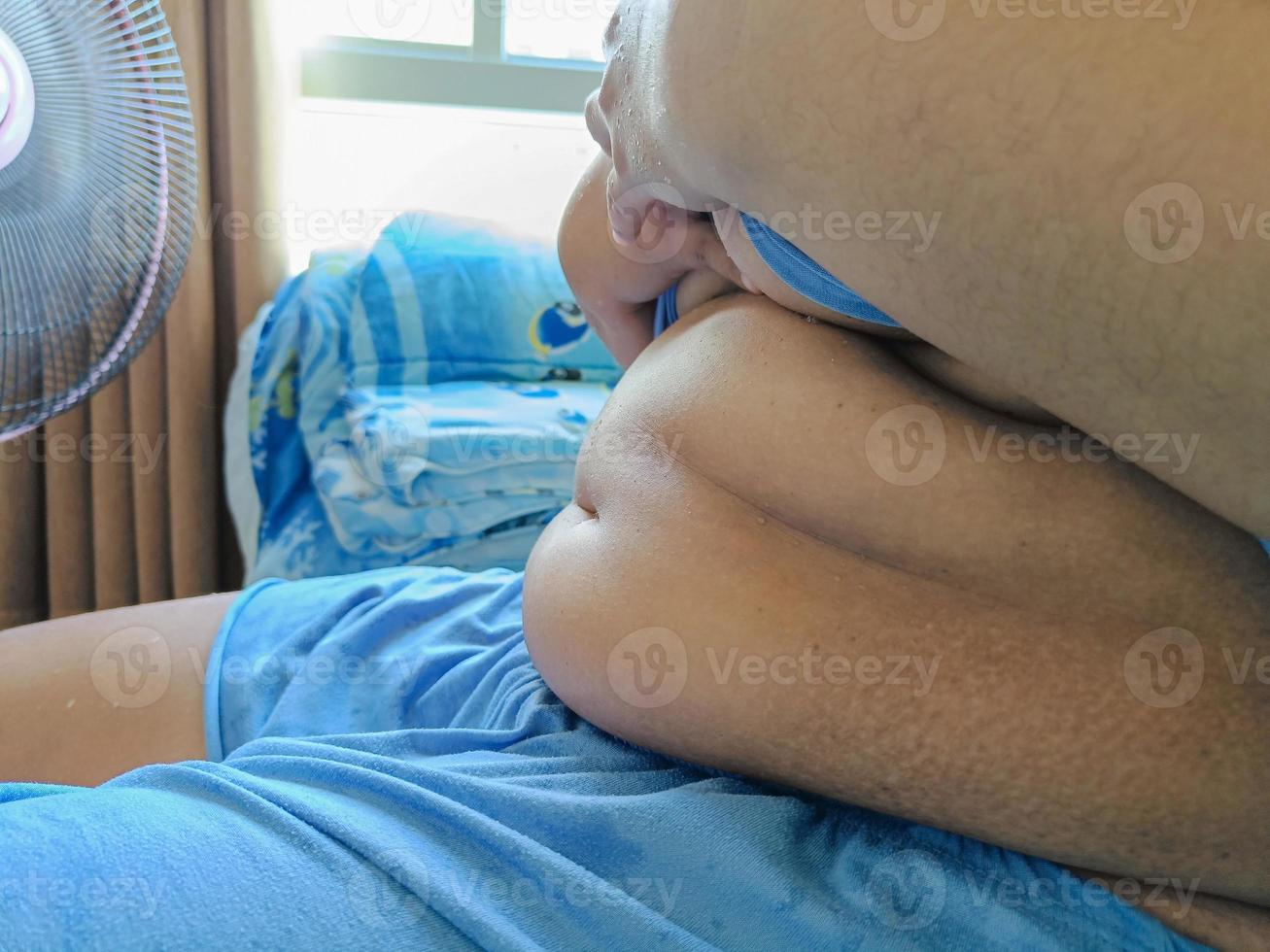 fet asiatisk kvinna sitter i sidled visar sin mage foto