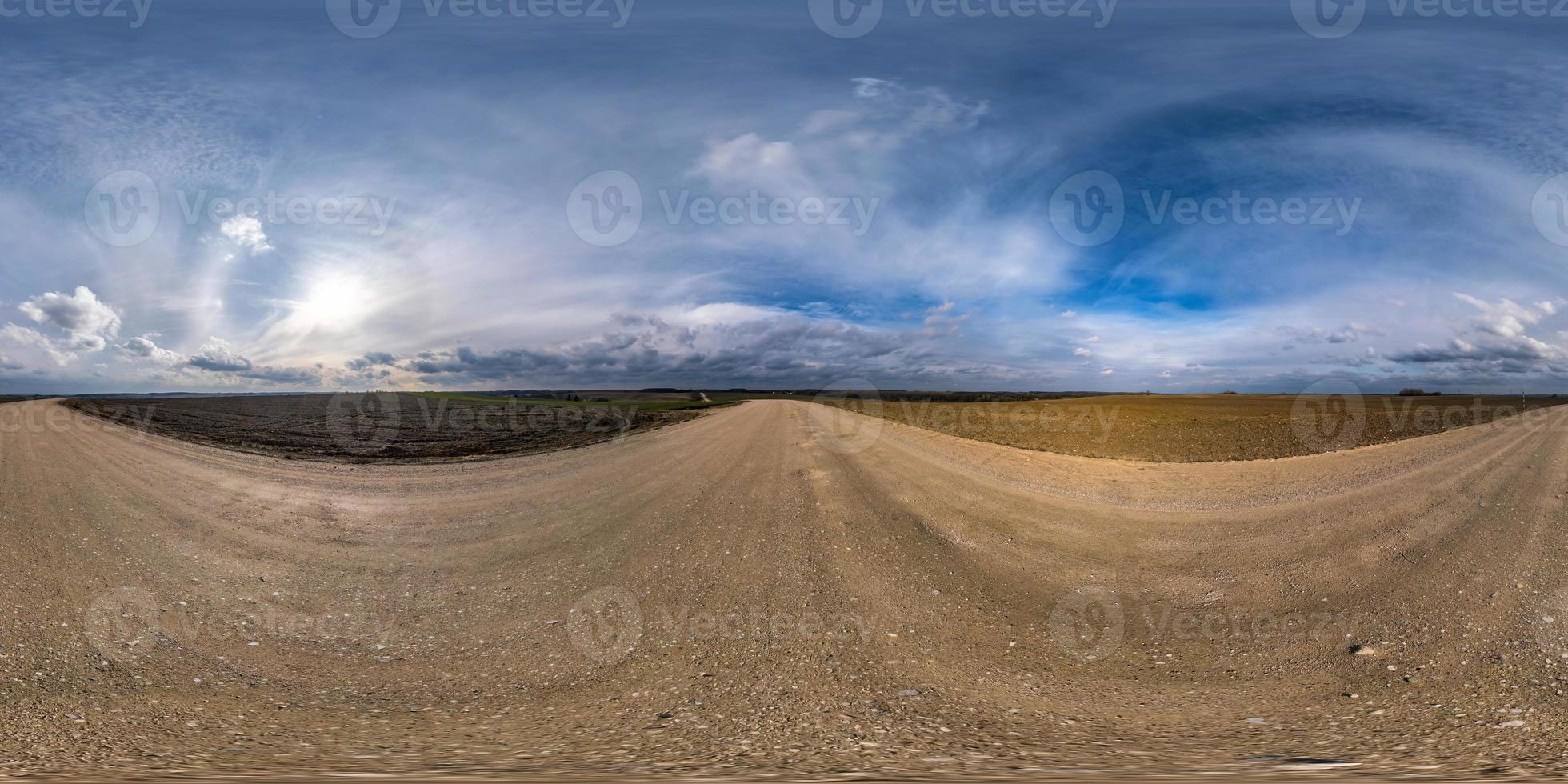 fullständig sömlös sfärisk hdri-panorama 360 graders vinkelvy på grusväg bland fält på vårdagen med fantastiska moln i ekvirektangulär projektion, redo för virtuell verklighetsinnehåll foto