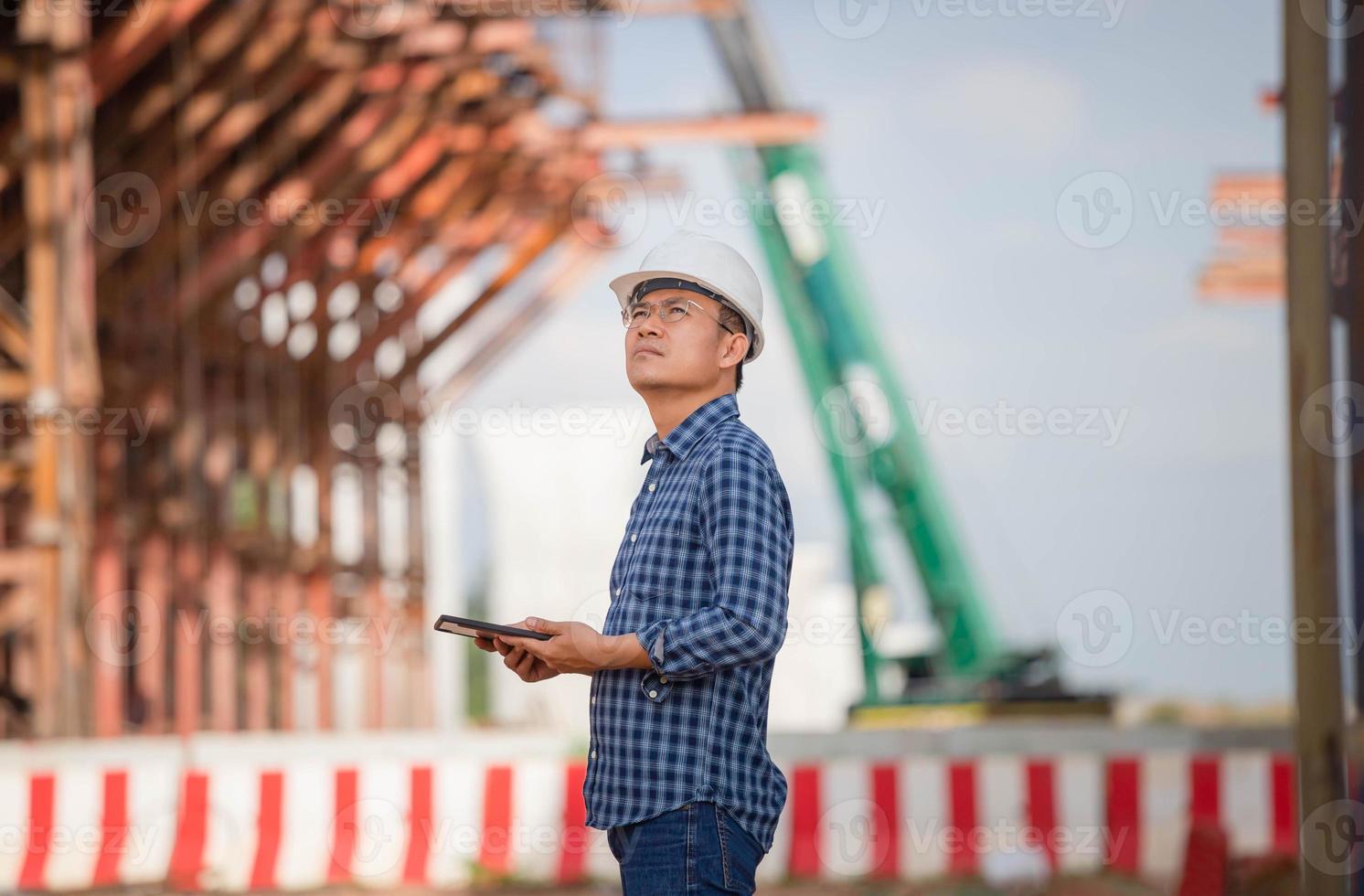 förmansarbetare i hjälm på infrastrukturbyggarbetsplatsen, byggnadsingenjör som kontrollerar projekt på byggarbetsplatsen, arkitekt med en digital surfplatta på en byggarbetsplats foto