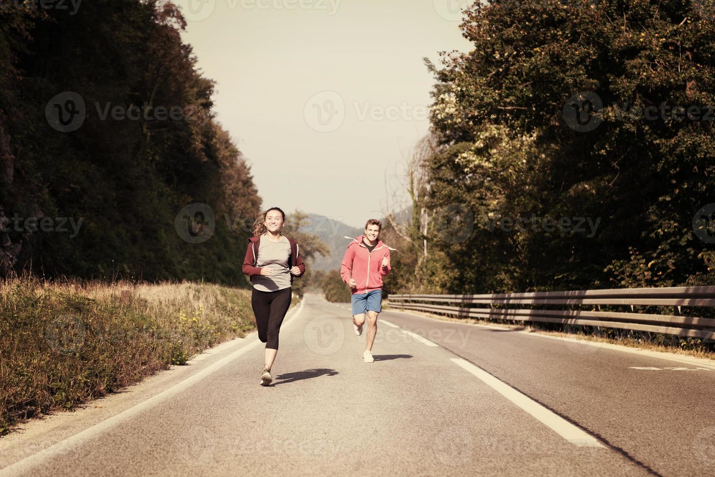 ungt par joggar längs en landsväg foto