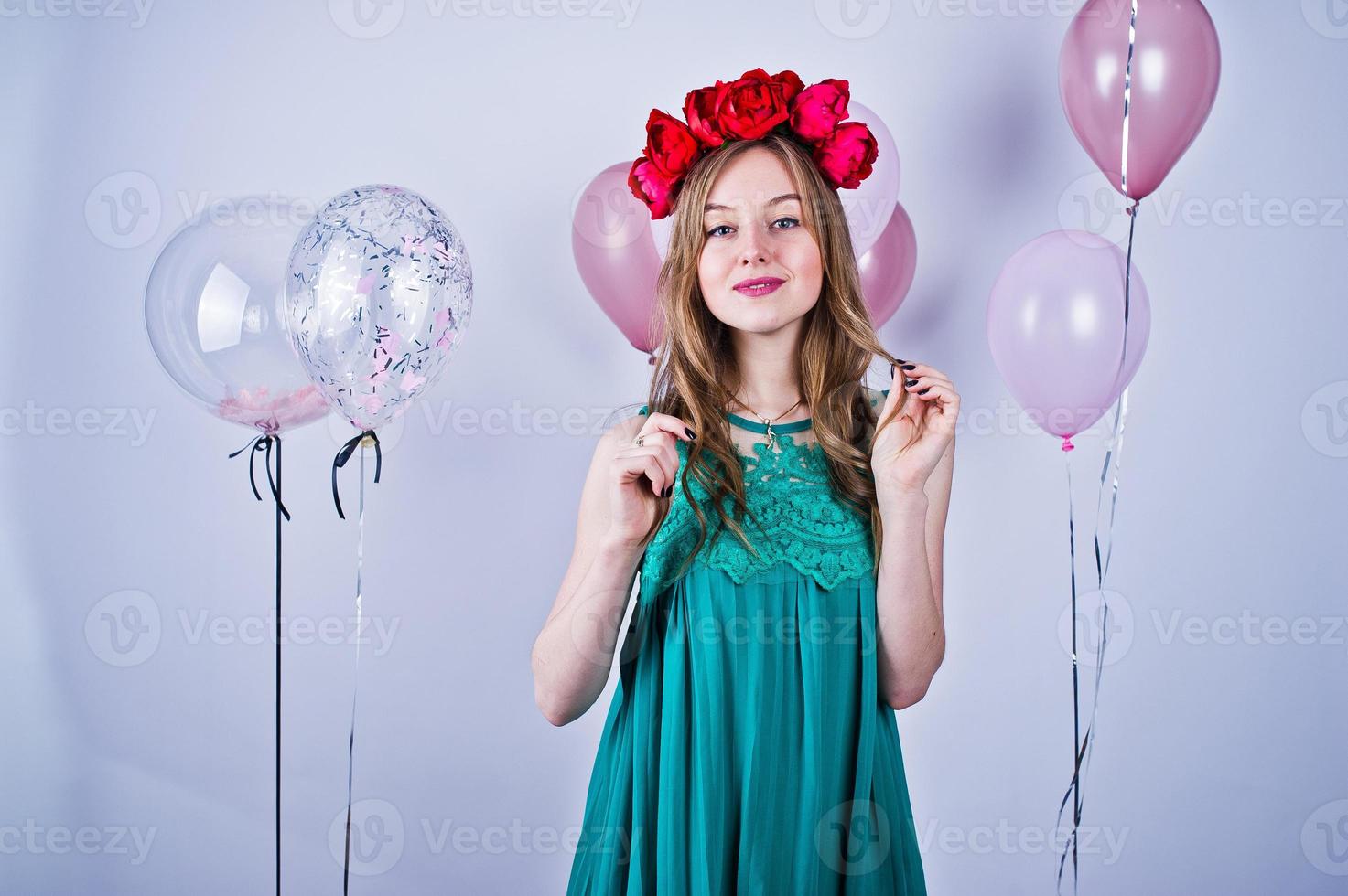 glad tjej i grön turkos klänning och krans med färgade ballonger isolerade på vitt. firande av födelsedagstema. foto