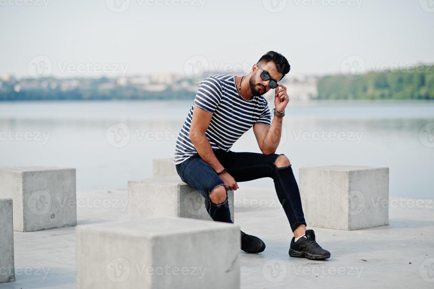 stilig lång arabisk skägg man modell på avskalad skjorta poserade utomhus. fashionabla arabisk kille vid solglasögon. foto