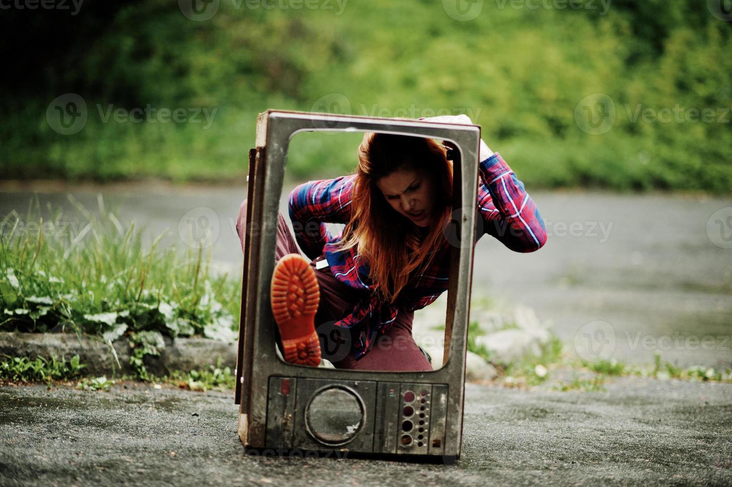 mode porträtt av rödhårig sexig tjej utomhus. modell attraktiv dramatisk kvinna med gamla tv-box. foto