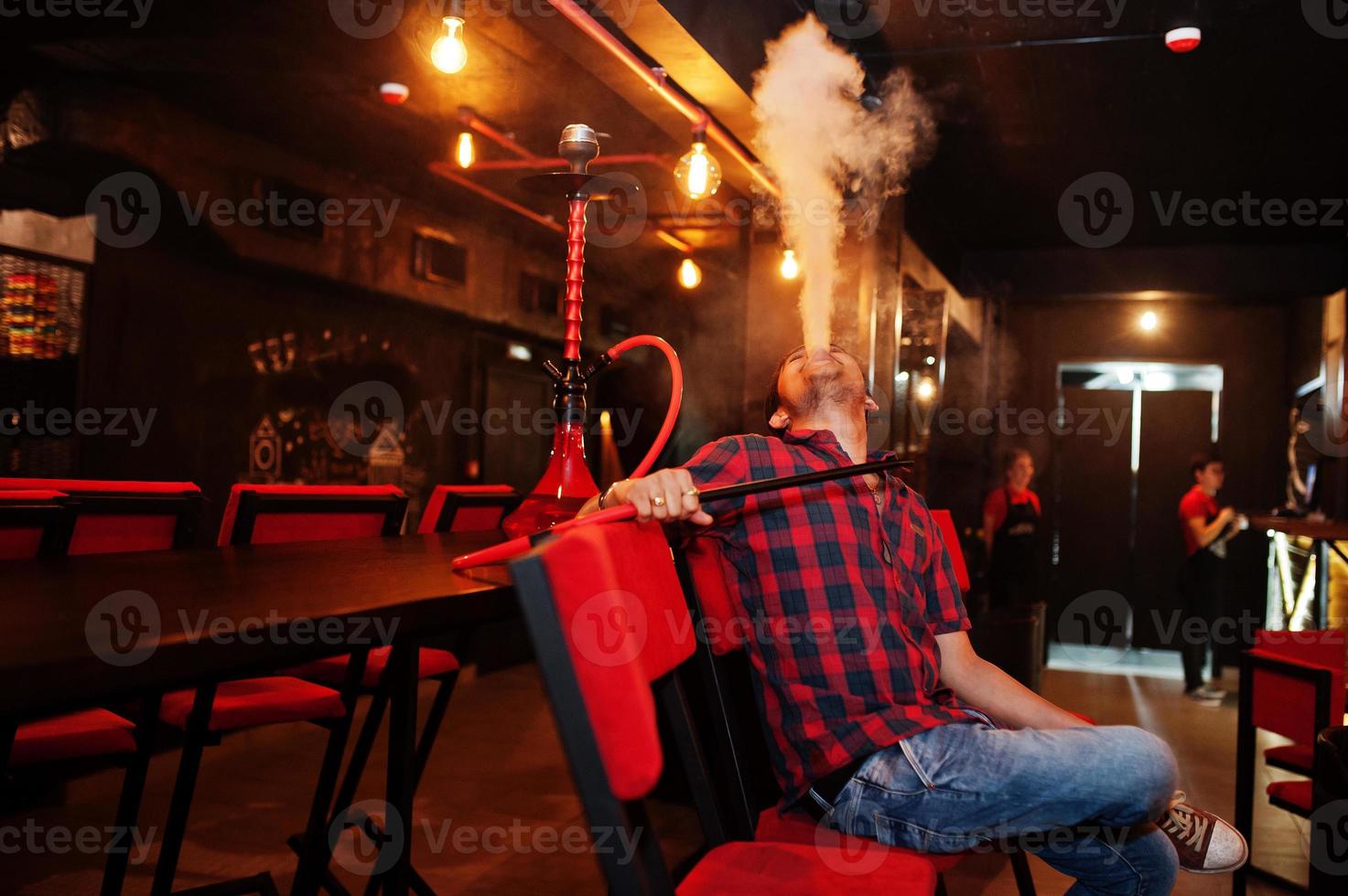 asiatisk man röker vattenpipa och vilar i loungebaren. foto