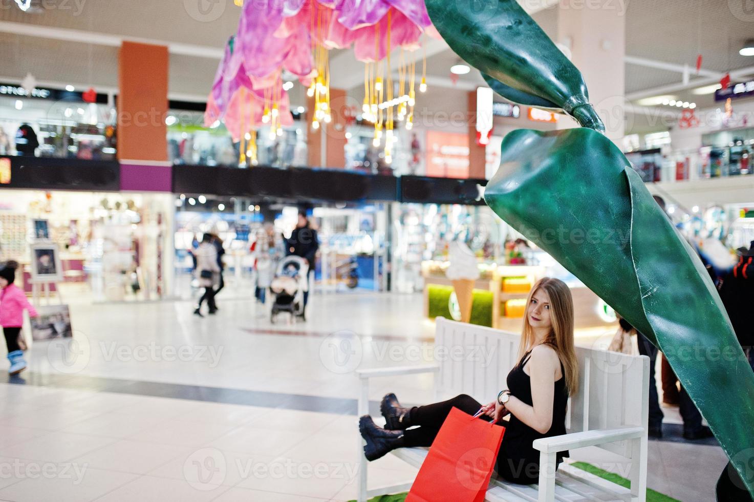 flicka med shoppingkassar i gallerian sitter på bänken. foto