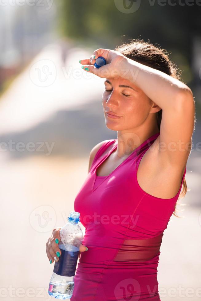 kvinna dricker vatten från en flaska efter jogging foto