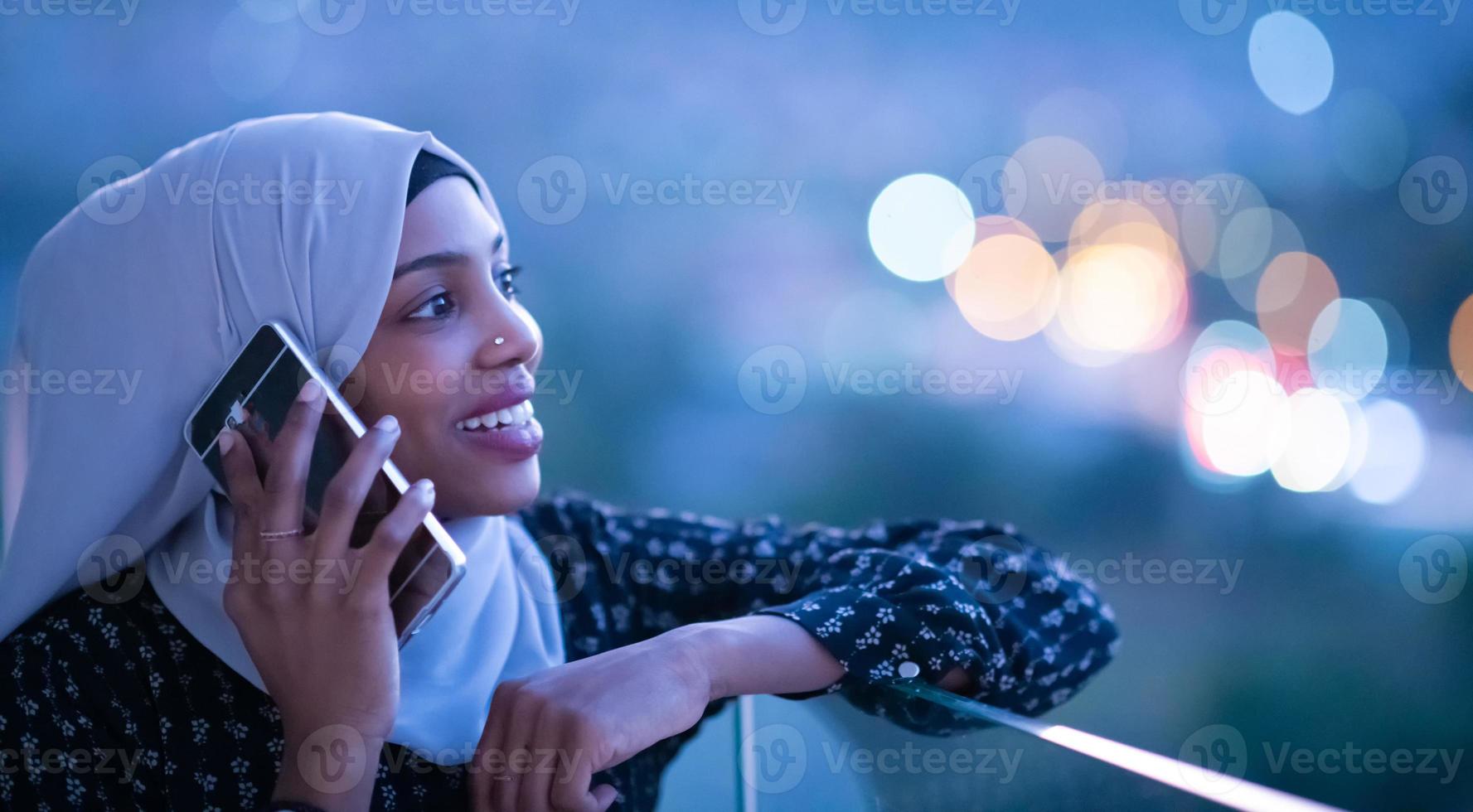 ung muslimsk kvinna på gatan på natten med telefonen foto