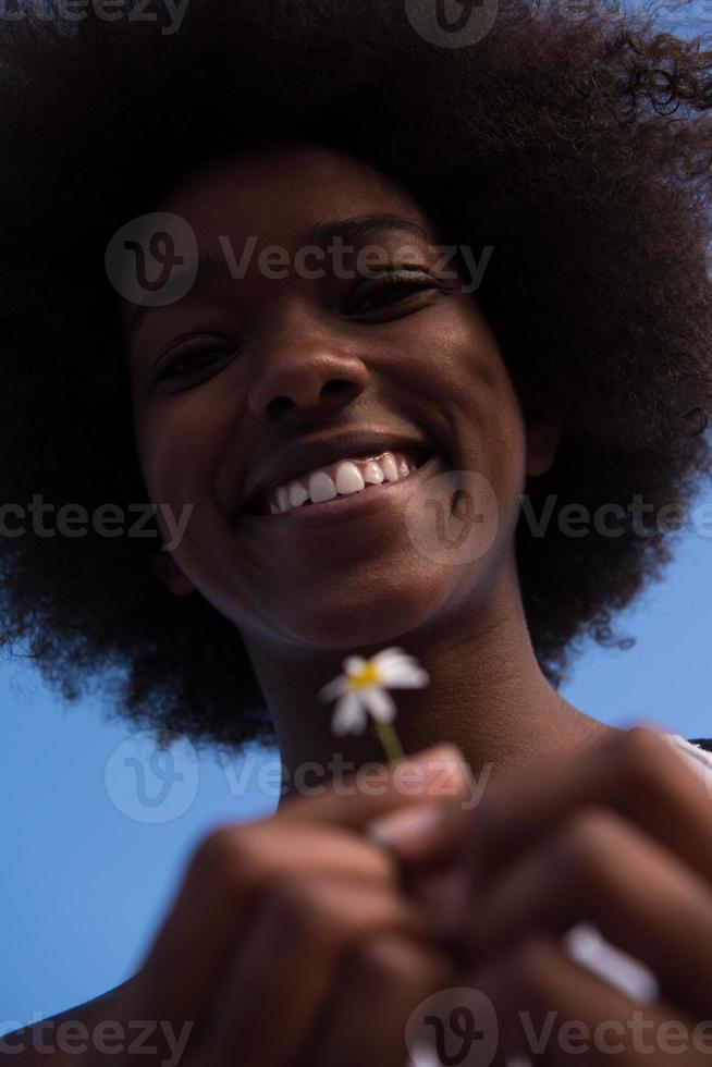 porträtt av afrikansk amerikansk flicka med en blomma i handen foto