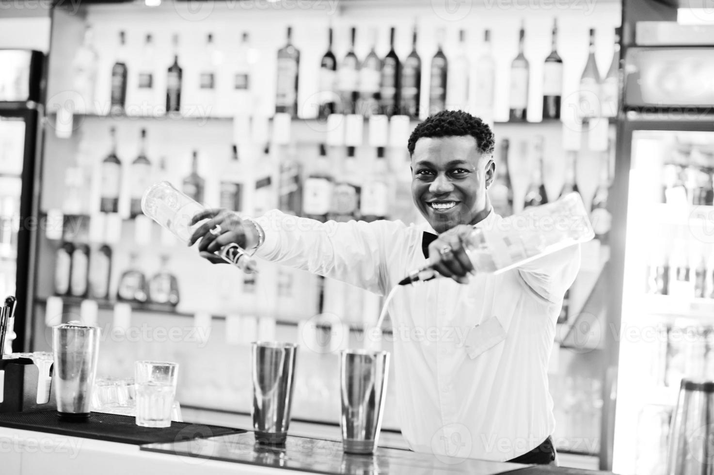 afroamerikansk bartender som arbetar bakom cocktailbaren. beredning av alkoholhaltiga drycker. foto