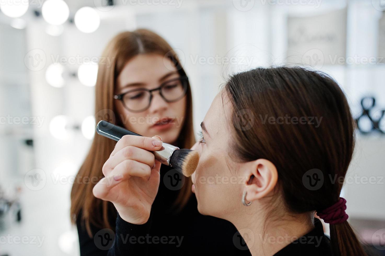 make up artist arbete i hennes skönhet visage studio salong. kvinna som ansöker av professionell make up master. skönhetsklubb koncept. foto