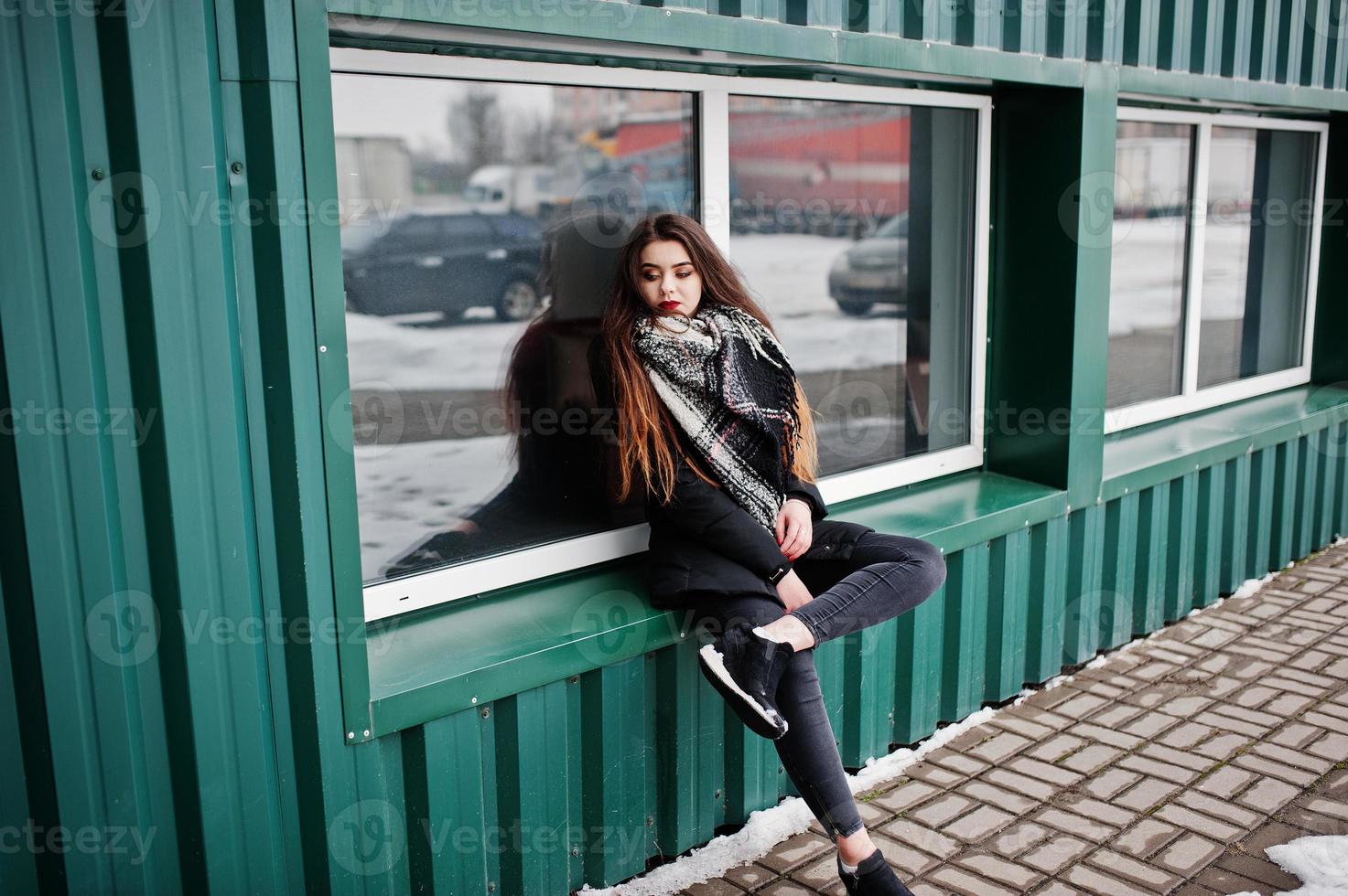 brunett snygg casual tjej i halsduk mot grön metallvägg. foto