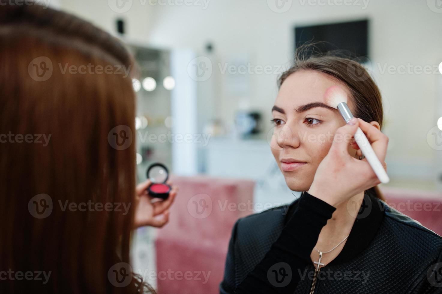 make up artist arbete i hennes skönhet visage studio salong. kvinna som ansöker av professionell make up master. skönhetsklubb koncept. foto