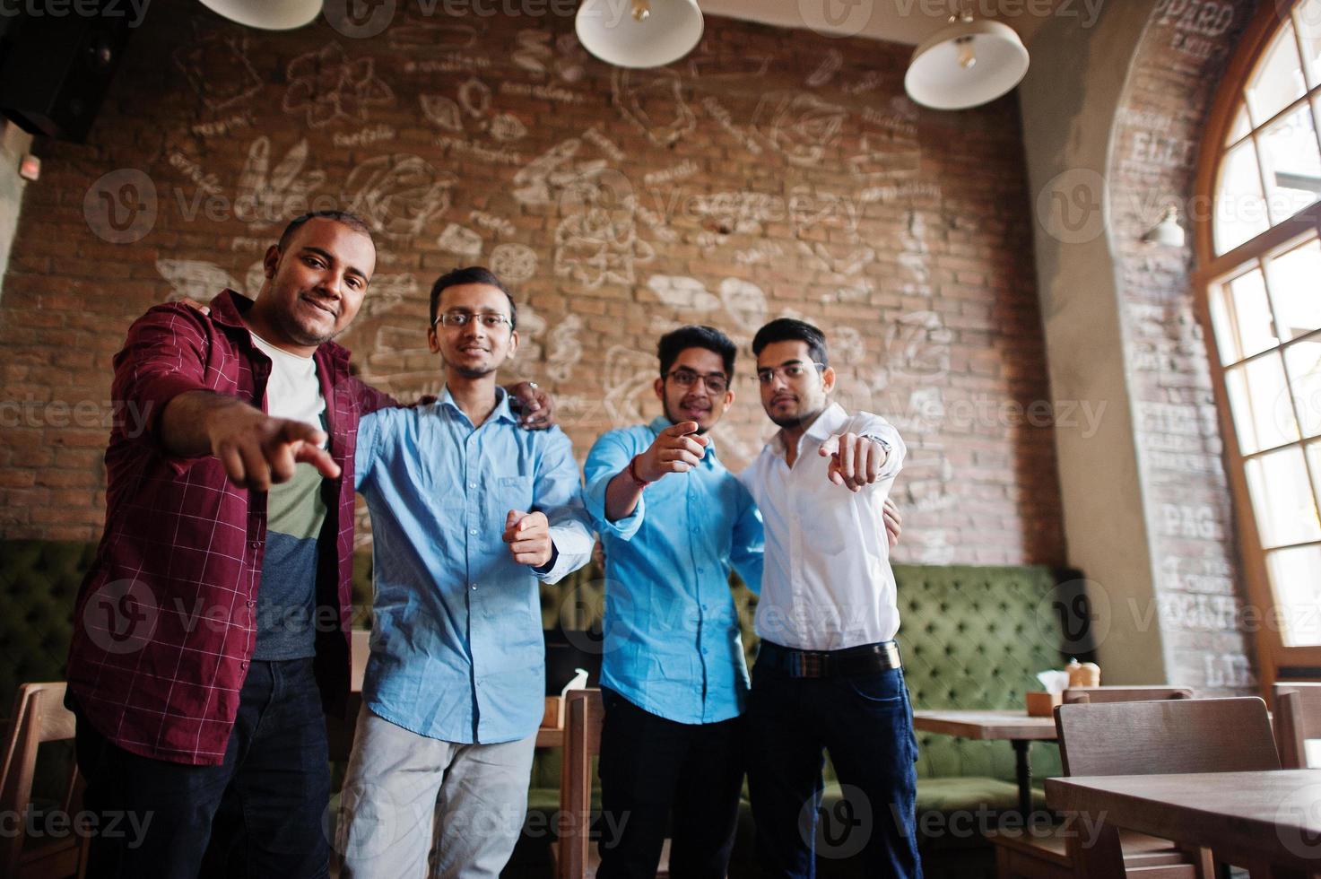 grupp av fyra sydasiatiska män poserade på affärsmöte i café. indianer som pratar. foto