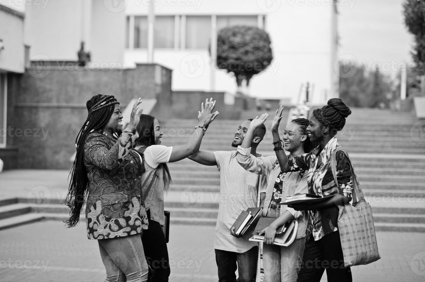 grupp på fem afrikanska högskolestudenter som spenderar tid tillsammans på campus på universitetsgården. svarta afro vänner studerar och ger high five varandra. foto