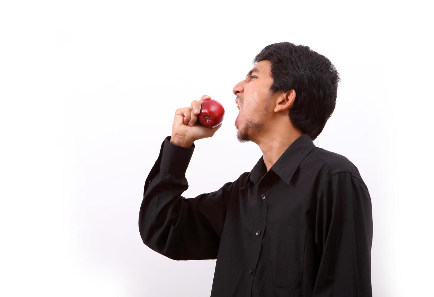 ung frisk man äter ett rött äpple foto